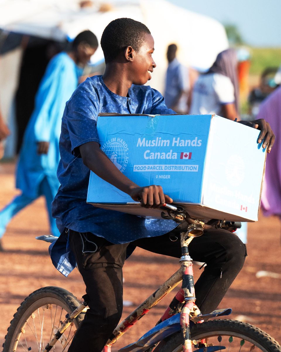 A boy cycling home with a Muslim Hands food parcel