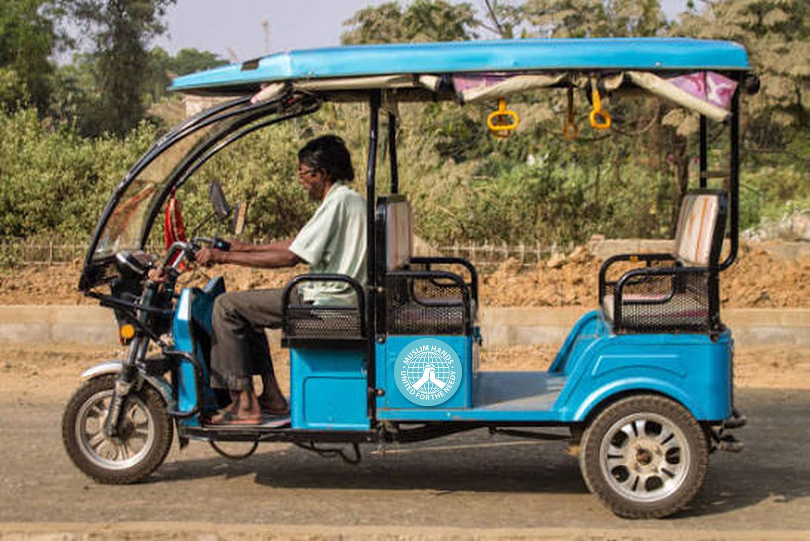 A driver in a new blue auto rickshaw